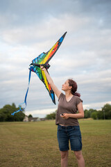 Teen age girl flying a colourful kite, summer time