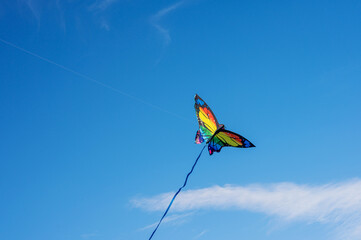 Flying rainbow butterfly kite, summer family fun activities, blue sky