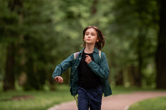 A child boy is running with wind blowing in his hair.