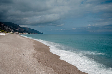 Serene Beach with Mountains and Cloudy Sky