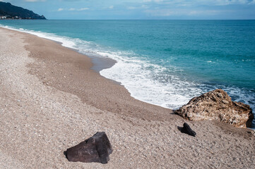 Tranquil Beach with Gentle Waves and Rocky Outcrops
