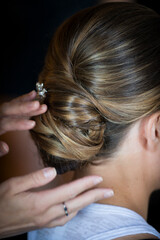 Fototapeta premium Stylist Adjusting Elegant Bridal Updo with Hairpin Detail
