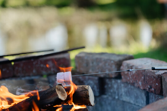 Roasting marshmallows at a lakeside brick fire pit at sunset