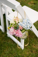 Pastel Ceremony Flowers Hanging on White Wedding Chair