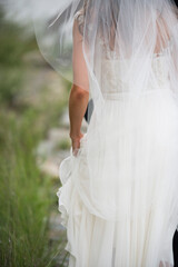 Bride Walking Outdoors with Flowing Veil and Lace Gown