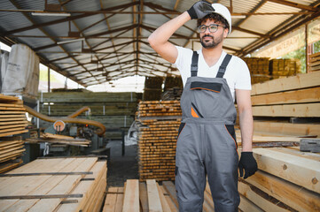 Carpenter wiping sweat from forehead in lumber warehouse
