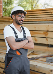 Woodworker smiling with crossed arms in lumber warehouse