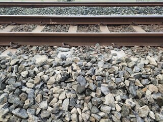A pile of ballast stones on a railroad pad. Ballast stones function to transmit the train's load to the underlying soil, absorb vibrations, maintain rail stability, and help with drainage.