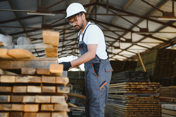 Carpenter checking lumber in warehouse, woodworking industry professional at work
