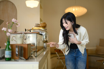 Happy asian female customer choosing a dessert in a cozy coffee shop
