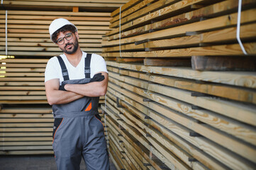 Woodworker posing with arms crossed in lumber warehouse