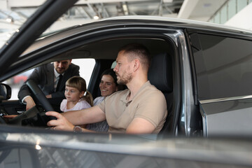 Happy family inside new car and salesman, selective focus