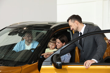 Salesman showing new car to happy family in salon