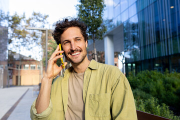 Smiling man talking on mobile phone outdoors in urban setting