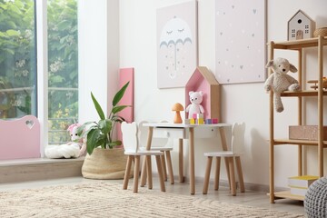 Contemporary furniture and decor near white wall in stylish playroom. Interior design