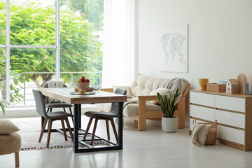 Wooden table, chairs, sofa and decor in dining room. Interior design
