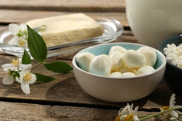 Different fresh dairy products and flowers on wooden table, closeup