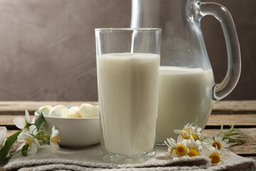 Fresh milk, mozzarella balls and flowers on wooden table, closeup. Dairy products