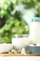Different fresh dairy products and flowers on white table outdoors, closeup