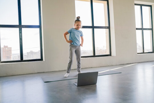 Child engaged in online learning while standing in a bright room with large windows - Powered by Adobe