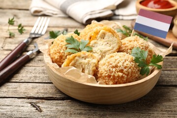 Delicious fried croquette balls, parsley and small flag of Netherlands on wooden table, closeup