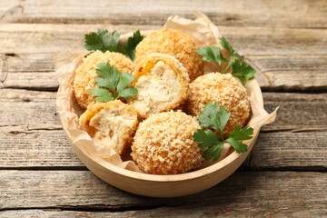 Delicious fried croquette balls with parsley on wooden table, closeup