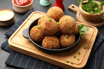 Delicious fried croquette balls with parsley and green onion on grey table, closeup