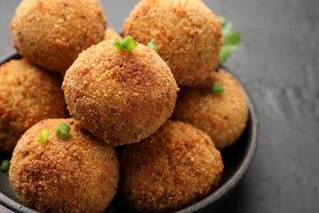 Delicious fried croquette balls with green onion on grey table, closeup