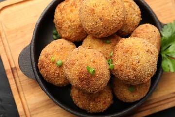 Delicious fried croquette balls with green onion on dark table, top view
