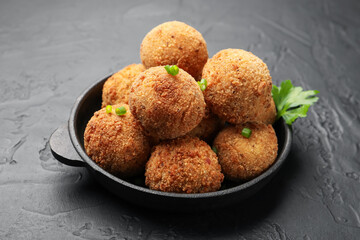 Delicious fried croquette balls with parsley and green onion on grey textured table, closeup