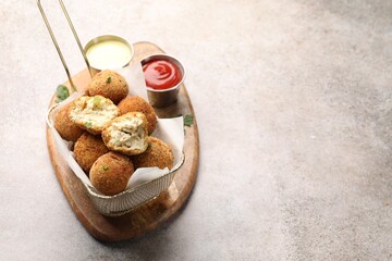 Delicious fried croquette balls with parsley and sauces on grey textured table, closeup. Space for...