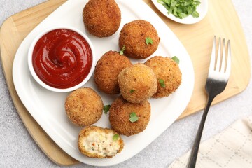 Delicious fried croquette balls with parsley and ketchup served on grey textured table, flat lay