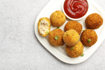 Delicious fried croquette balls with parsley and ketchup on grey textured table, top view. Space for text