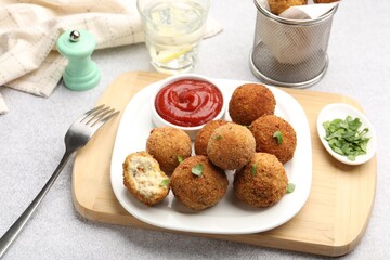 Delicious fried croquette balls with parsley and ketchup on grey textured table, closeup