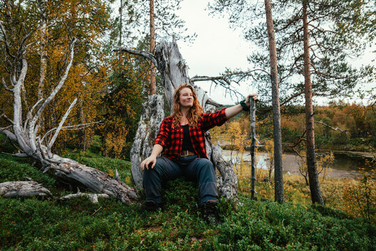 Hiker resting on fallen tree throne in autumn forest near &aring;re,