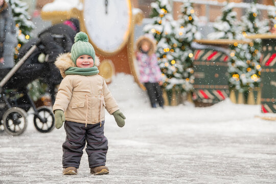 happy toddler walks at a Christmas city fair in the snow