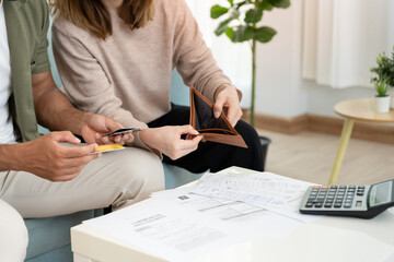 Stressed and headache asian couple with large bills or invoices no money to pay to expenses and...