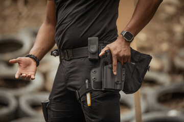 A man dressed in tactical gear adjusts a holstered pistol