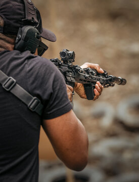 A man in tactical gear aims a rifle at a target during target practice