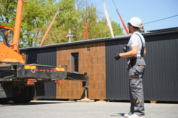 Construction worker supervising loading of modular house onto truck