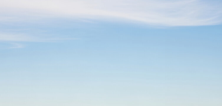 Light blue sky with a few wispy clouds drifting high above, creating an airy and open atmosphere suitable for minimalist backgrounds or serene design compositions.