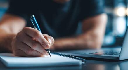 Fototapeta premium Close up of focused man hand writing on notebook with pen at desk