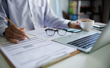 asian businessman checking report documents making business plan using laptop working on desk at home office, work at home concept