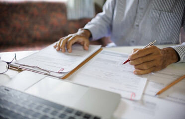 asian businessman checking report documents making business plan using laptop working on desk at home office, work at home concept