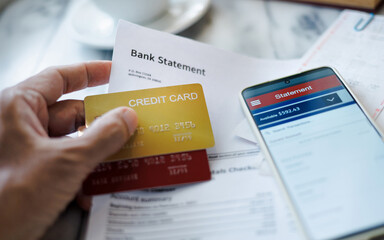 man hand holding credit card with bank statement report using smart phone checking balance via...