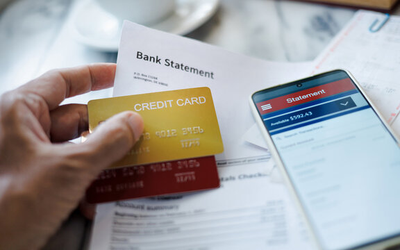 man hand holding credit card with bank statement report using smart phone checking balance via mobile app, online shopping concept and paying - Powered by Adobe