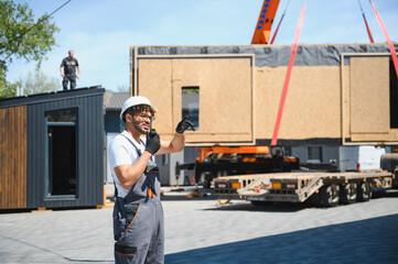 Construction worker directing modular house placement onto truck