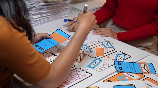 Designers refining mobile app user interface with paper prototypes