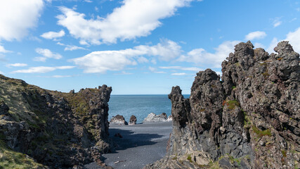 Volcanic lava formations on Djupalonssandur beach, set against the rugged coastline of Snaefellsnes peninsula in Iceland's Snaefellsjokull National Park.