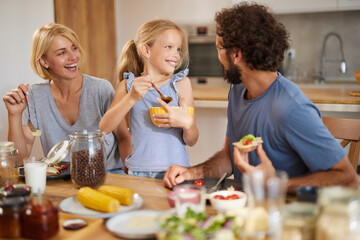Family members gather at the kitchen table for a delightful meal, enjoying food and engaging in...